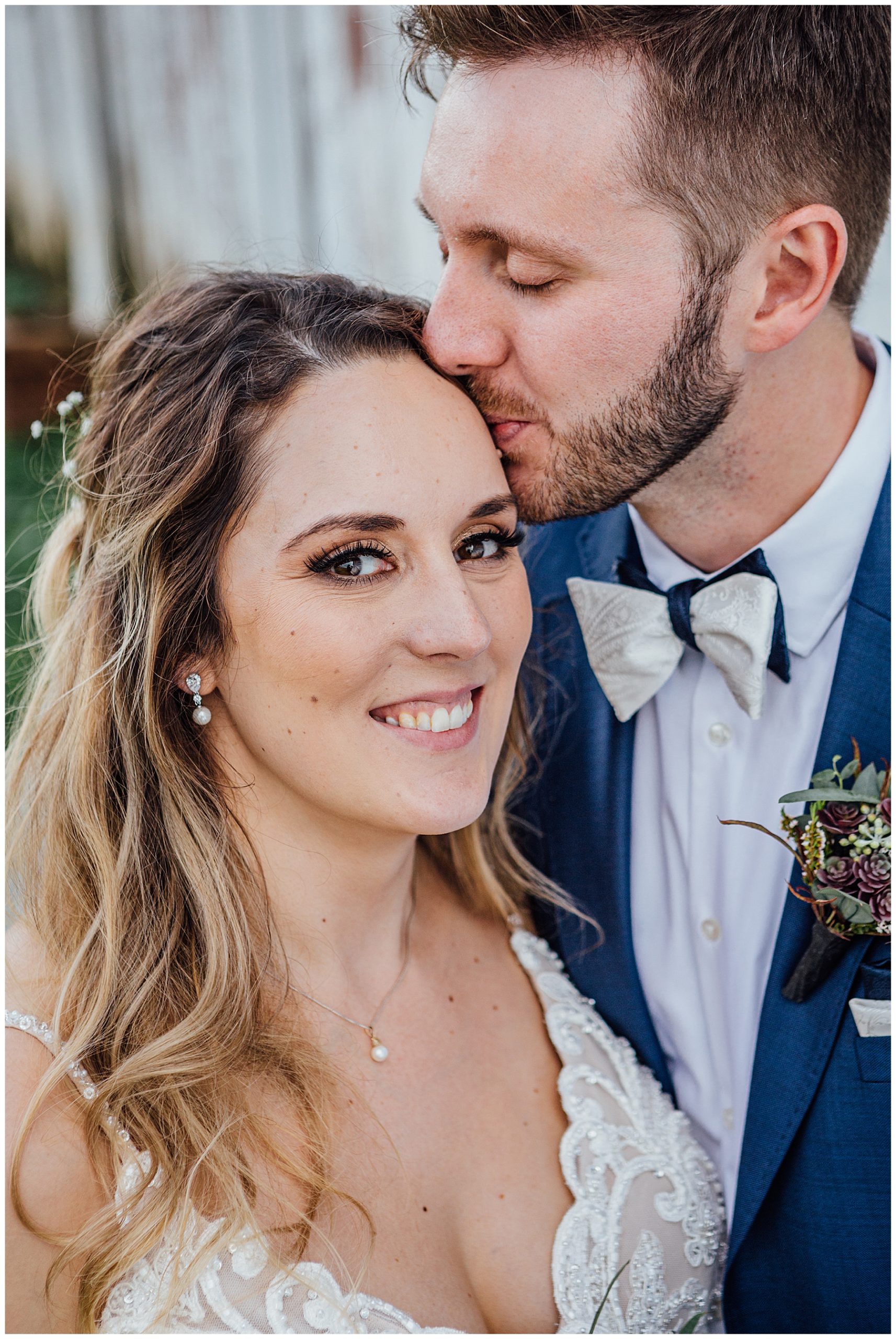 Groom kissing Bride infront of barn