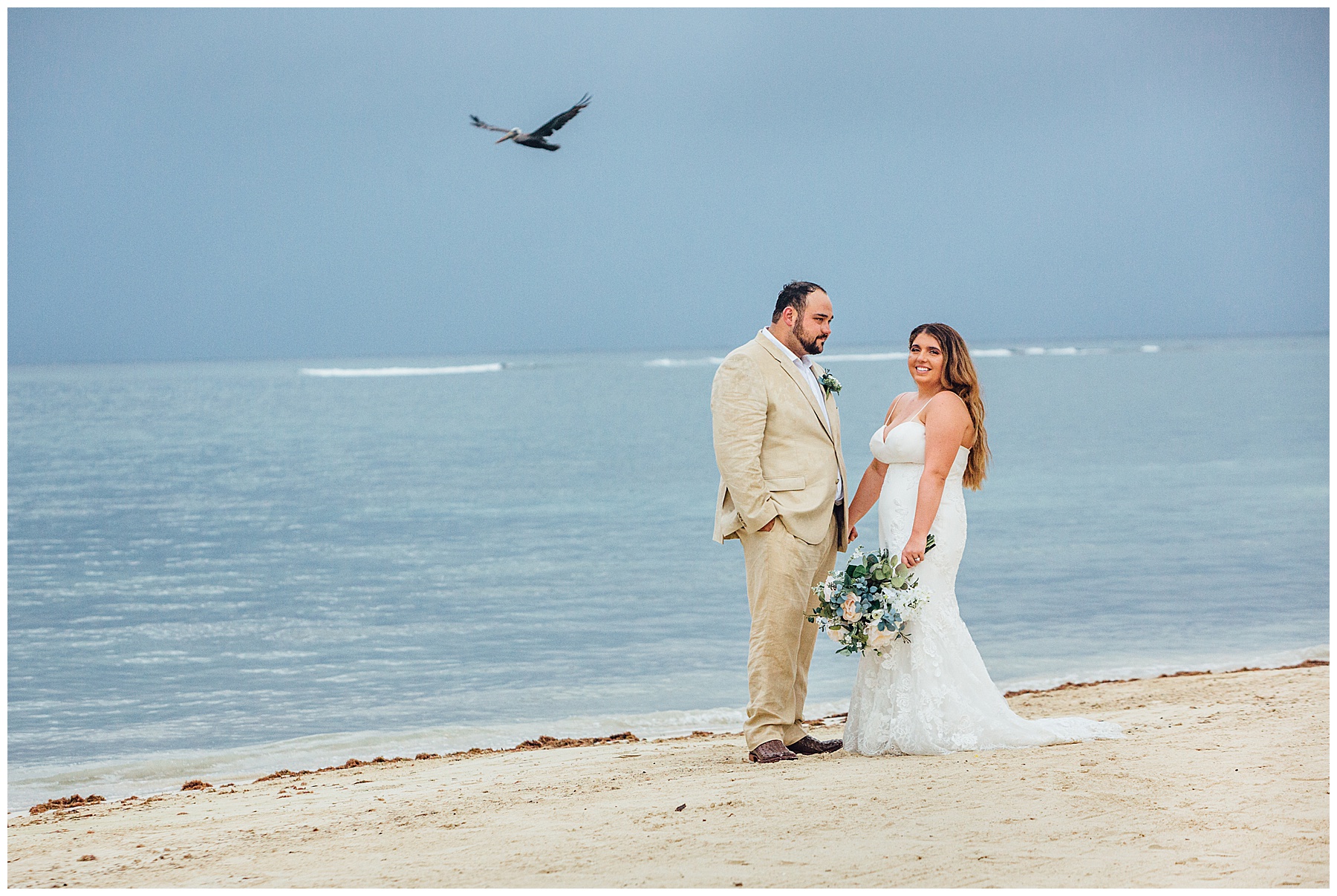 Bride and groom on beach with a seagul in background